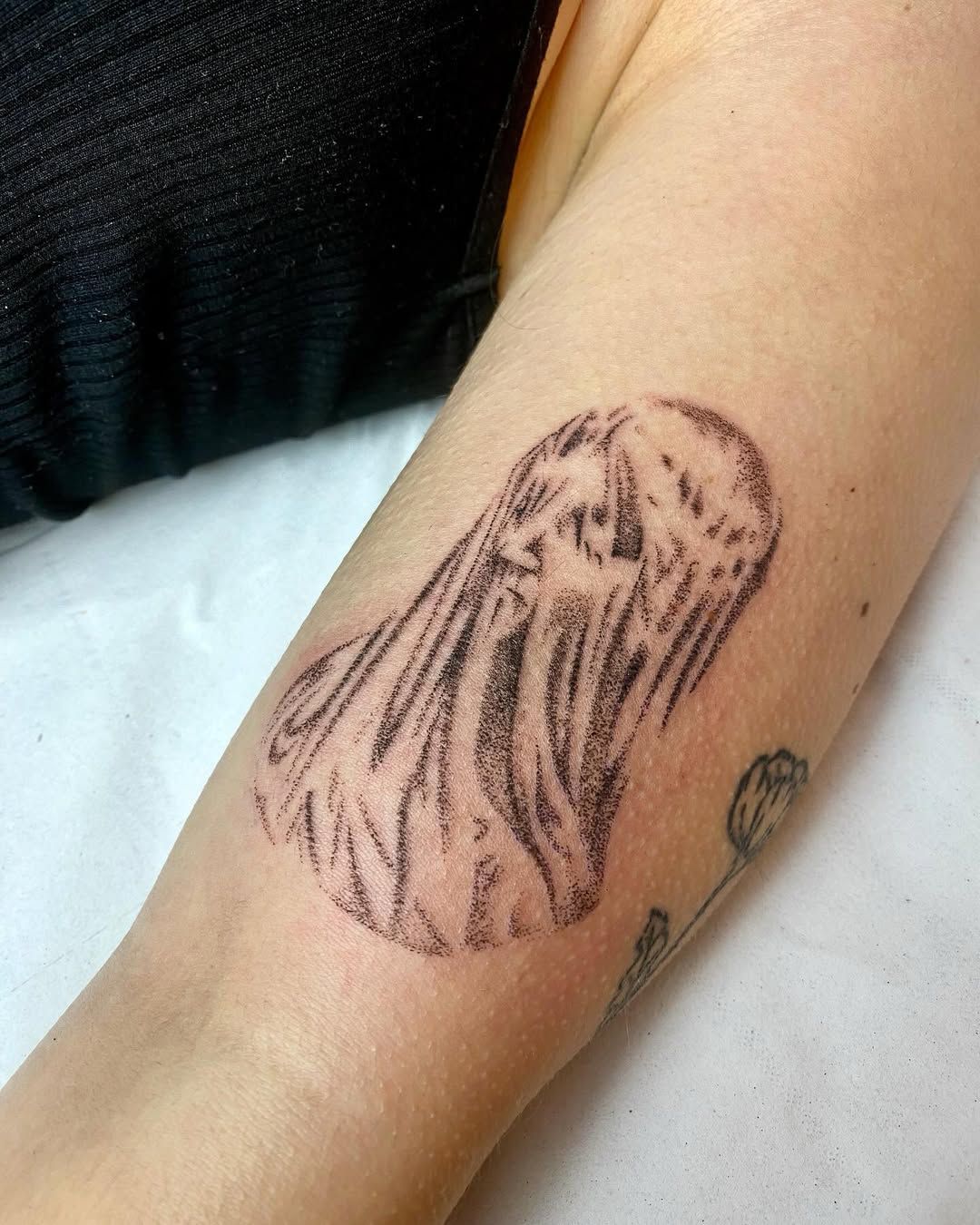 Tatouage handpoke d’un fantôme drapé sur un avant-bras.