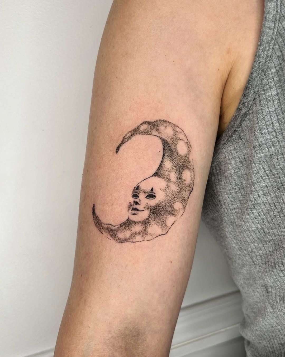 Croissant de lune avec un visage, tatouage handpoke sur un bras.
