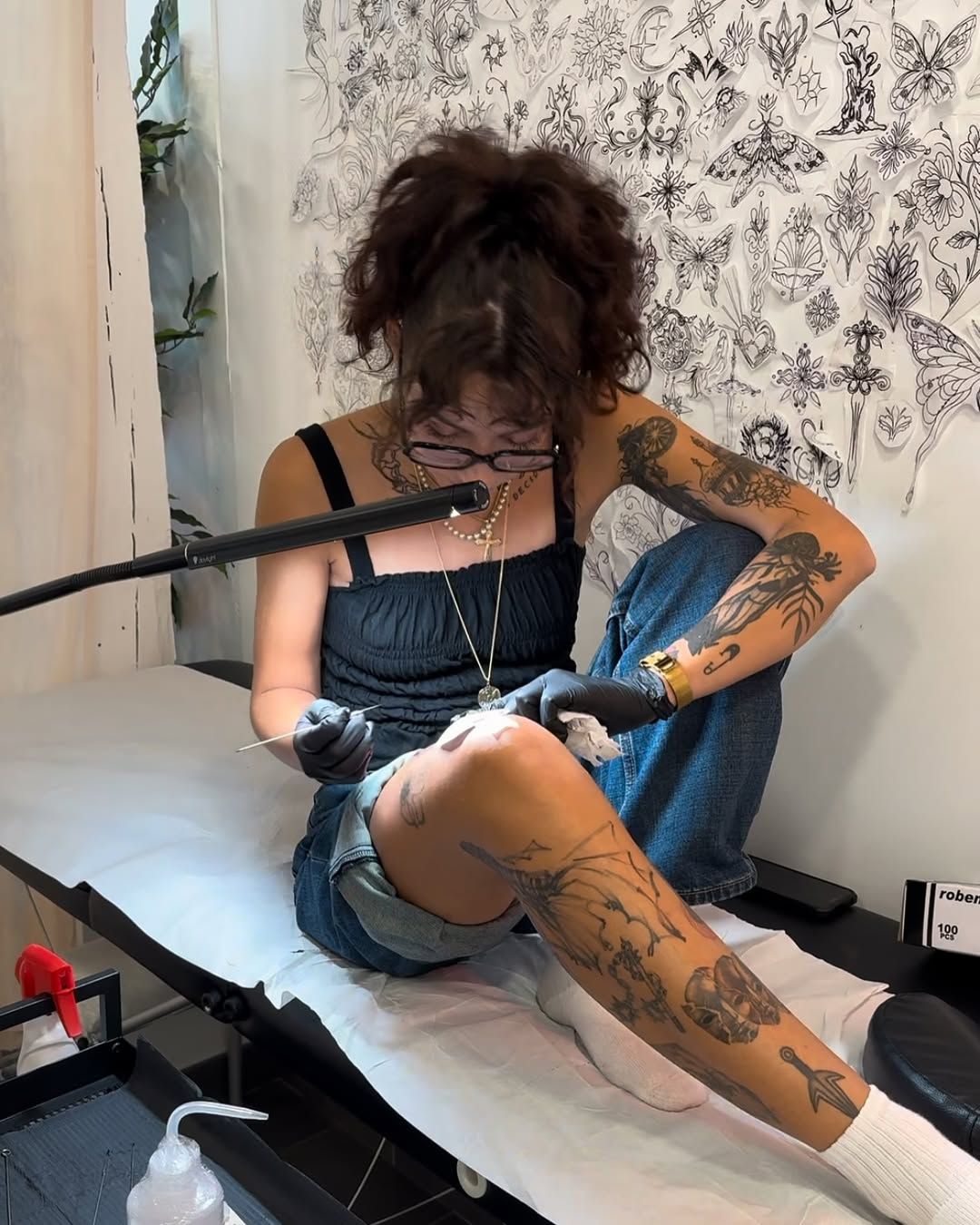 Alexandra concentrée sur un tatouage handpoke en studio.